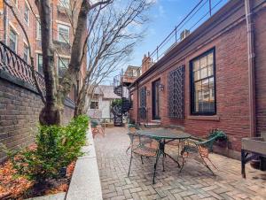 eine Terrasse mit einem Tisch und Stühlen neben einem Backsteingebäude in der Unterkunft Beacon Hill: The Aldrich House in Boston