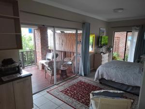 a bedroom with a bed and a sliding glass door at Pebbles and Shells in Chintsa