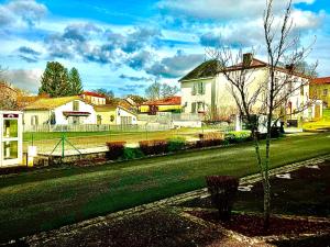 ulica z domami i drzewem przed domem w obiekcie Gîte des Lavandes w mieście Oradour-Fanais