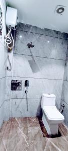 a bathroom with a toilet and a phone on the wall at Hotel Orio Castle in Ludhiana