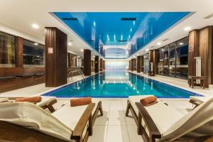 a swimming pool in a hotel with chairs and a swimming pool at Bansko lodge 500m from ski lift in Bansko +9 photos