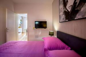 ein Schlafzimmer mit einem rosa Bett und einem TV in der Unterkunft Apartman Candy Split with jacuzzi and parking place in Split