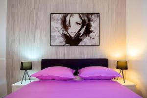 ein Bett mit rosa Kissen und ein Gemälde darüber in der Unterkunft Apartman Candy Split with jacuzzi and parking place in Split