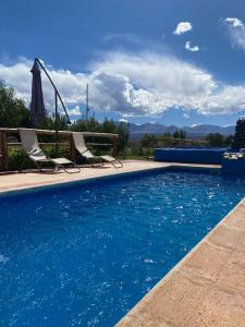 a swimming pool with two chairs and an umbrella at Complejo HUNUC in Calingasta