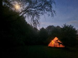 a lit up tent in a field at night at Tente glamping "bluebird" à la Ferme de la Chevêche in Fosses-La-Ville