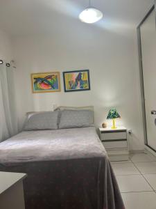 Un dormitorio con una cama y una mesa con una lámpara. en Apartamento Itapema centro, en Itapema
