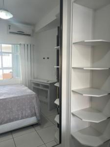 1 dormitorio con 1 cama, ventana y estanterías en Apartamento Itapema centro, en Itapema 12 fotos más