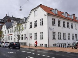 a person in a red jacket walking in front of a white building at Craizy Hans in Odense