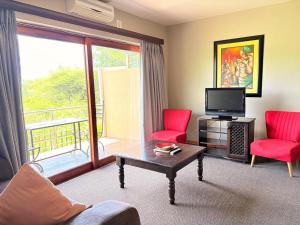 a living room with two red chairs and a television at Rio Vista Lodge in Malelane