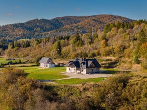 two houses in a field with a mountain in the background at Smerek 119- Baza Przy Szlaku in Smerek