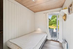a small bedroom with a bed and a window at Cozy House On Helgenæs With Sea View in Knebel