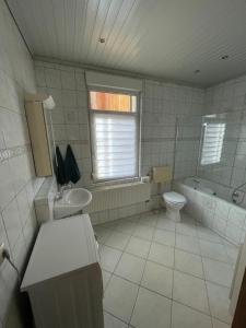 a bathroom with a sink and a toilet and a tub at Ferienwohnung in Schmölln zentrale Lage in Schmölln