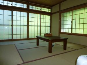 um quarto com uma mesa em frente às janelas em Anzuan Nishida em Ueda