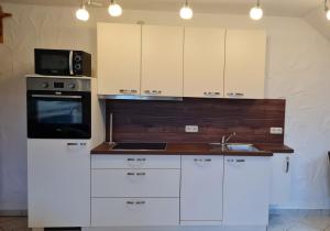 a kitchen with white cabinets and a microwave and a sink at Campingplatz Jurahöhe in Pottenstein