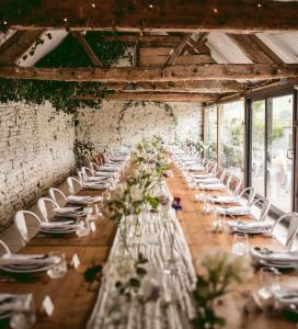 a long table with white chairs and flowers in a room at Wilde Lodge By Birch Stays in Bucknell