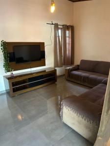 Una sala de estar con un sofá y un televisor de pantalla plana. en Casa Al Mare, en Itanhaém