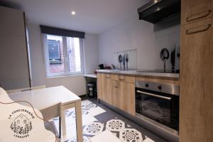 a kitchen with a table and a stove and a counter top at Le Grenier, appartement de charme, centre de Lens in Lens