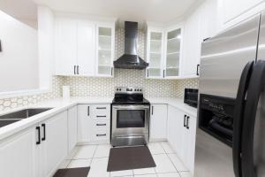 una cucina con mobili bianchi e un forno a piano cottura di Beautiful Home by Toronto in Central Location a Brampton Altre 34 foto