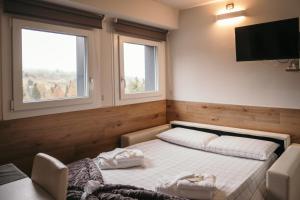 a bedroom with a bed with two chairs and a television at App Panoramico 300 mt dalle Piste Relax e Vista Alpi in Passo del Tonale