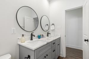 ein weißes Badezimmer mit einem Waschbecken und 2 Spiegeln in der Unterkunft NEW Acadian House KING Bed Cajun Luxury Nespresso in Lafayette + 20 Fotos