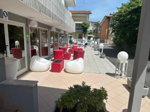 eine Gruppe von roten und weißen Stühlen außerhalb eines Gebäudes in der Unterkunft hotel roby in Rimini