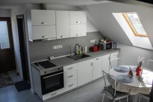 a kitchen with white cabinets and a table and a window at Sàndor-lak apartman in Ciceu