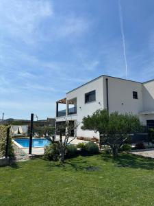 a white house with a swimming pool in a yard at Villa C'est la vie in Kaštela