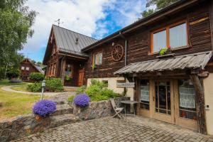 a wooden house with purple flowers in front of it at Kapteinis&Grants in Engure