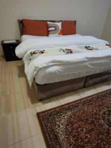 a bed in a bedroom with a rug on the floor at جناح فاخر غرفتين نوم وصالة تلفزيون in Rayyis