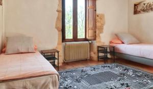 ein Zimmer mit zwei Betten und einem Fenster in der Unterkunft Maison de charme à Puy-l'Évêque avec piscine partagée in Puy-lʼÉvêque