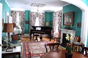 a living room with green walls and a grand piano at Auberge Chesley's Inn in Cornwall