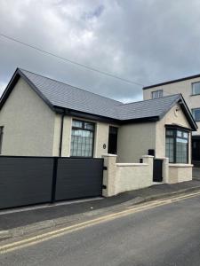 a white house with a black roof and a garage at The Cottage Central Newcastle, 4-Star Accommodation by Tourism Northern Ireland in Newcastle