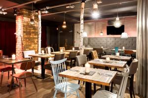 a restaurant with wooden tables and chairs and lights at pentahotel Brussels City Centre in Brussels