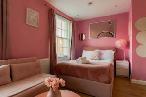 a bedroom with pink walls and a bed and a couch at Gloucester Place Studios in London