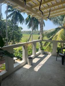 a porch with palm trees and a bench on it at Heena villa in Kamburugamuwa