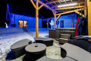 Patio cubierto con mesas y bancos en la nieve en ZinHouse Wojakowa, en Wojakowa