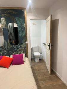 a bedroom with a bed with two pillows and a toilet at Chambre indépendante proche du Circuit des 24h et du Pôle Européen du Cheval in Yvré-lʼÉvêque