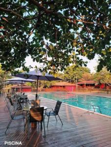 a table and chairs with umbrellas next to a swimming pool at Refúgio em Barreirinhas Chalé in Barreirinhas
