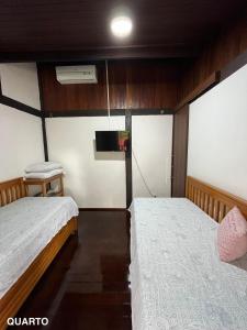two beds in a small room with a tv at Refúgio em Barreirinhas Chalé in Barreirinhas +36 photos