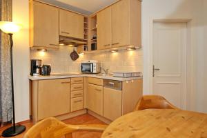 a small kitchen with wooden cabinets and a table at Dünenschloss Wohnung 2-11 in Kühlungsborn