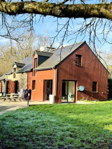 un grande fienile rosso con un edificio di La Lande d'Ouée - Sauna & Convivialité a Saint-Aubin-du-Cormier