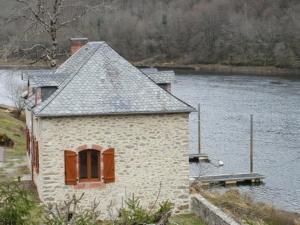a building on the side of a body of water at Maison du meunier in Soursac