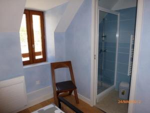 a bathroom with a chair and a glass shower at Maison du meunier in Soursac