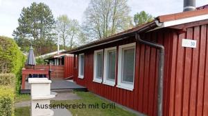 a red cabin with a porch and a deck at Möwe 30 in Mirow