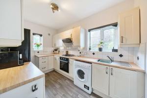 a kitchen with white cabinets and a washer and dryer at Lovely spacious 3 double bed flat, LS17 in Leeds
