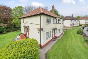 a small white house with a grass yard at Lovely spacious 3 double bed flat, LS17 in Leeds