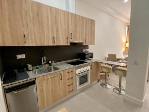 a kitchen with wooden cabinets and a sink at Palangreros Beach Apartment in Fuengirola