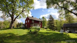 a red house on a green field with trees at Henneviken BnB in Ed