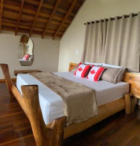 a bedroom with a wooden bed with red pillows at Mundarium - Chalés Temáticos com Hidromassagem e Cromoterapia in Santo Antônio do Pinhal