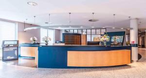 a lobby with a blue counter in a building at PLAZA INN Heidehof in Hermannsburg